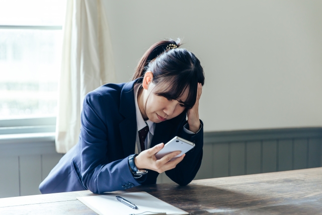 スマホ 頭抱える女子学生